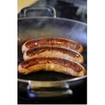 Three long sausages, sizling in a pan on top of a gas stove.