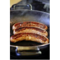 Three long sausages, sizling in a pan on top of a gas stove.