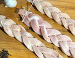 Thre platts of pork rind tied with string on a butchers copping block